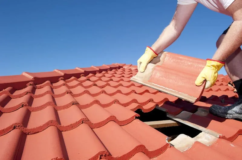 A worker is replacing the roof tile